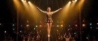 Female circus performer balancing on tightrope under spotlight with audience cheering in background. Professional acrobat entertainment show concept.