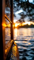 Raindrops on window glass at sunset with golden light reflecting on water surface, creating atmospheric mood with bokeh effect and water ripples in background.