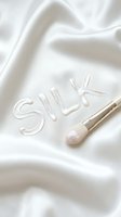 Silk text formed with cosmetic product on luxurious white fabric with makeup brush, representing skincare, beauty, and textile luxury for cosmetics and fashion marketing.