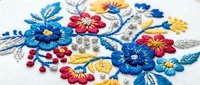 Colorful hand embroidered floral design with blue, red and yellow flowers on white fabric. Traditional needlework craft art for textile decoration projects.