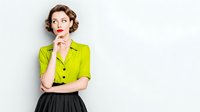 Thoughtful woman in bright lime green blouse and black skirt against white background, hand on chin in contemplative pose. Retro-inspired business attire.