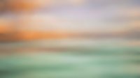 Soft blurred ocean sunset background with pastel teal water and warm orange sky tones, perfect for overlays, web design, and calm mood boards.