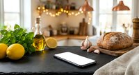 Modern kitchen counter with fresh ingredients, smartphone and warm lighting creating cozy cooking atmosphere for culinary content and food preparation.