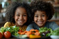 Two cheerful African American children smiling near fresh vegetables and salad ingredients on kitchen table, promoting healthy eating habits and family cooking.