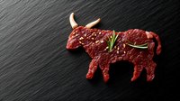 Raw beef steak cut in shape of bull with rosemary on black slate background. Creative food concept for steakhouse menu or butcher shop.