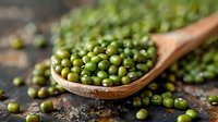 Fresh green mung beans in wooden spoon on rustic background, nutritious legumes for healthy cooking and plant-based protein source.