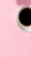 White ceramic cup of fresh black coffee with foam bubbles on pink background, minimalist composition with copy space for text or design elements.