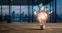 Glowing light bulb with digital innovation icons on wooden desk in modern office overlooking city skyline at sunset for business technology concepts.