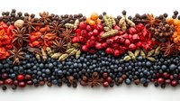 Colorful arrangement of fresh berries, star anise, and spices creating decorative border pattern on white background, suitable for seasonal food design and packaging.