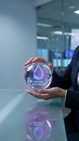 Businessperson holding glowing crystal sphere with water security icon and purple droplet symbol in modern office environment for sustainability and environmental protection concepts.