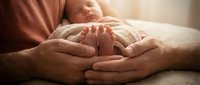 Young newborn infant's foot resting in parents' hands, symbolizing family bonding, parental care, and new life. Suitable for family, healthcare, and parenting content.