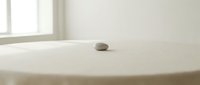 Minimalist zen stone on white bathtub edge in bright bathroom interior for spa relaxation and wellness meditation concepts.