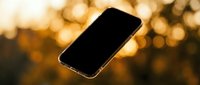 Smartphone with blank screen floating against warm golden bokeh background, suitable for app mockups, technology marketing, and digital product presentations.