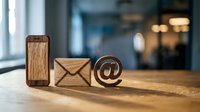 Wooden communication icons on office desk featuring phone, email envelope and at symbol for digital marketing and business contact concepts.