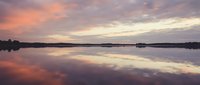 Serene lake at sunrise with mirror-like water reflecting vibrant orange and purple clouds, peaceful nature landscape for meditation and relaxation projects.