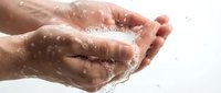 Cupped hands catching fresh clean water with splashing droplets against white background for hygiene and wellness concepts.
