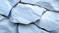 Broken chunks of white chalk or limestone with rough textured surfaces and deep shadows creating dramatic natural patterns and layers in close-up view.