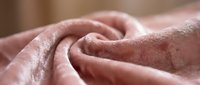 Soft pink plush fabric with luxurious texture folded in elegant curves, showcasing rich velvet or fleece material for home decor and textile design projects.