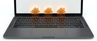 Three wooden house models positioned on laptop keyboard representing real estate technology, property investment, online mortgage applications, digital home buying process.