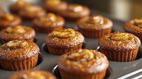 Homemade chocolate muffins topped with caramel sauce and nuts in baking tin, fresh baked dessert with golden topping, close up view of sweet pastry.