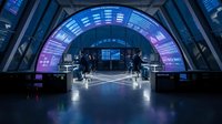Futuristic sci-fi corridor with neon blue and purple lighting, modern architecture tunnel with glass panels and metallic framework for technology concepts.