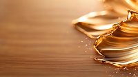Liquid gold metallic splash on wooden surface creates dynamic motion with droplets and waves in warm amber tones against natural wood texture background.
