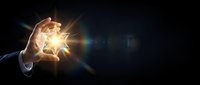 Businessman hand holding glowing light bulb against dark background, representing innovation, ideas, and creative business solutions for corporate design projects.