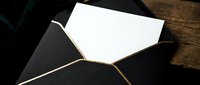 Black envelope with white letter paper on wooden surface for elegant correspondence and formal communication.
