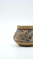 Ancient ceramic bowl with blue spiral and leaf motifs on natural clay, isolated on white background for design, decor, and cultural heritage projects.