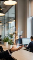 Businessman holding glowing digital network nodes and connected lines above palm in modern office workspace with colleagues and computers in background for technology and innovation concepts.
