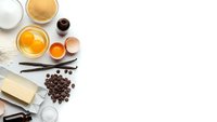 Baking ingredients arranged on white background including eggs, flour, butter, milk, vanilla, chocolate chips and spices for homemade cooking recipes.