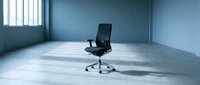 Empty modern office space with single black executive chair on concrete floor, blue walls, and natural light from window. Suitable for corporate, business, and workspace concepts.