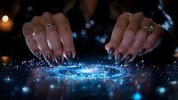 Female hands with manicure creating magical glowing blue light effect on dark background, mystical energy sparkles and particles flowing between fingers.