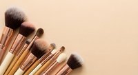 Professional makeup brushes with rose gold ferrules arranged on neutral beige background for beauty and cosmetics applications.