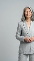 Confident mature Asian businesswoman in gray suit smiling professionally against neutral background for corporate marketing materials.