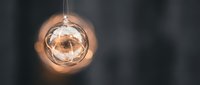 Transparent glass sphere ornament with warm golden light glowing inside, hanging decoration for holiday season, festive home decor.