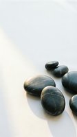 Smooth dark stones arranged on white surface, isolated design element for wellness, spa, meditation and relaxation concepts.