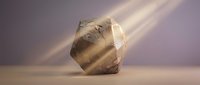 Translucent quartz crystal with warm golden light rays passing through, casting shadows on neutral surface for mineral and geology concepts.