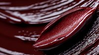 Dark red tulip petals with water drops in dramatic macro photography, creating abstract natural curves and reflective surfaces against deep burgundy background.