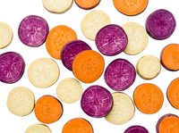 Colorful carrot slices in purple, orange and white varieties arranged on white background. Fresh organic root vegetables cut in rounds showing natural patterns.