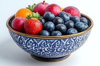 Fresh mixed berries and fruits in ornate blue and white ceramic bowl against white background, featuring blueberries, strawberry, apples and kumquat.