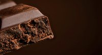 Rich dark chocolate bar with airy bubbled texture and glossy surface on warm brown background for confectionery and dessert marketing materials.
