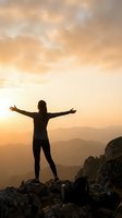 Woman hiker celebrating success on mountain summit with arms raised during golden hour sunrise, freedom and achievement concept for wellness motivation.
