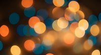 Colorful bokeh lights background with warm orange and cool blue circular light spots creating dreamy atmosphere for holiday celebrations and festive designs.