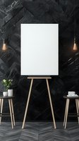 Blank white canvas on wooden easel against dark textured wall with pendant lights and decorative side tables. Modern art studio or gallery mockup setup.