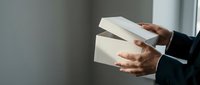 Professional businessman hands holding white envelopes in modern office setting for corporate correspondence and business communication purposes.