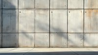 Modern concrete wall with rectangular panels and subtle shadows cast on textured gray surface, industrial architectural detail with minimalist aesthetic and floor space.