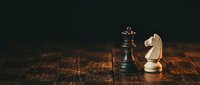 Chess pieces king and knight on wooden board representing strategic thinking and business competition in corporate environment.