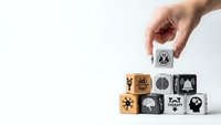 Hand placing wooden cube with brain icon onto stack of blocks featuring mental health and psychology symbols on white background.