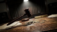 Wooden gavel and legal documents on judge desk in courtroom with dramatic lighting for law and justice concepts in legal proceedings.